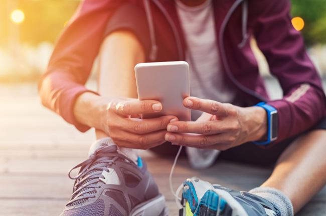 Träningsklädd person som sitter ner och håller en mobiltelefon