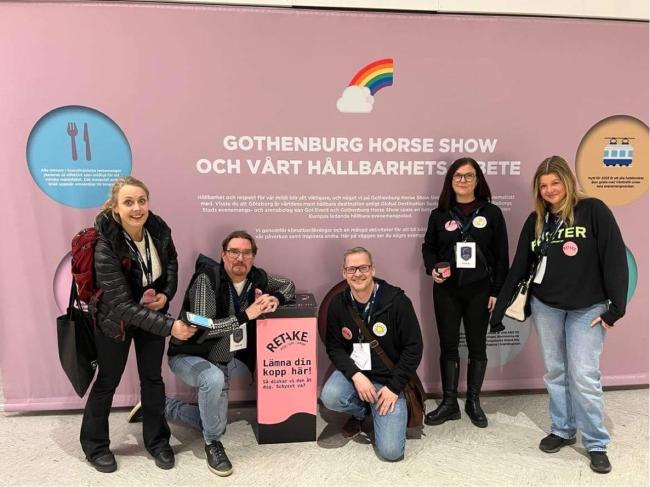 Grupp av fem människor framför affisch vid Gothenburg Horse Show